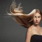 beautiful model with long smooth flying blonde hair isolated dark grey studio background young caucasian model with well kept skin hair blowing air