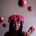 selective focus photography of woman wearing flower headband holding apple fruit