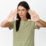serious woman stretch out hands block stopping say no frowning looking displeased standing white background
